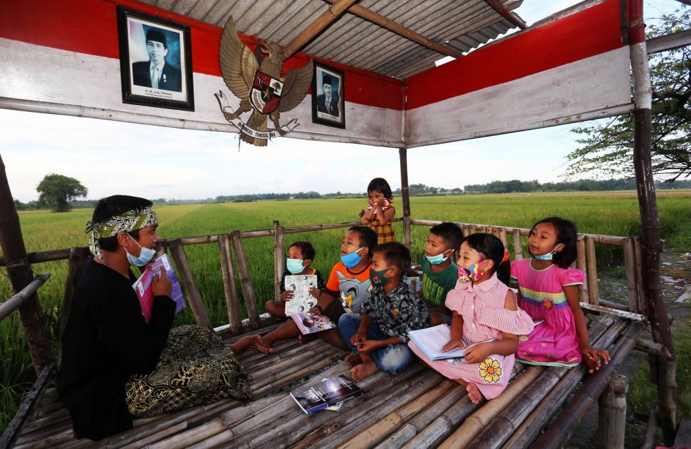 Belajar di tengah sawah dengan suasana pedesaan bersama Irfandi (kiri) owner dari Gubuk Kampung Lali Gadget. Dalam memperingati hari pendidikan nasional belajar tak garus di sekolah bisa dimana saja, dengan suasana baru yang kondusif anak-anak akan lebih mudah memahami pelajaran, Tampak gubuk untuk belajar di area sawah yang berlokasi di dusun Bendet desa Pagerngumbuk kecamatan Wonoayu Sidoarjo. (02/05/21) FOTO: Guslan Gumilang/Jawa Pos